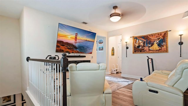 cinema room featuring light hardwood / wood-style flooring and ceiling fan