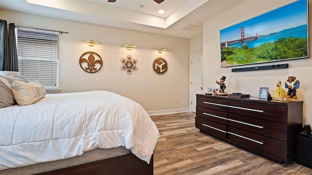 bedroom featuring light hardwood / wood-style flooring and a raised ceiling