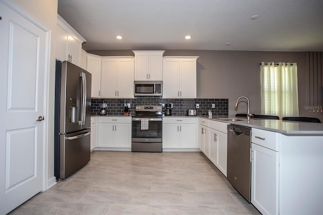 kitchen with sink, white cabinetry, stainless steel appliances, decorative backsplash, and kitchen peninsula