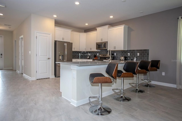 kitchen with appliances with stainless steel finishes, white cabinets, a kitchen breakfast bar, and kitchen peninsula