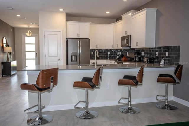 kitchen with stainless steel appliances, a kitchen breakfast bar, kitchen peninsula, and white cabinets