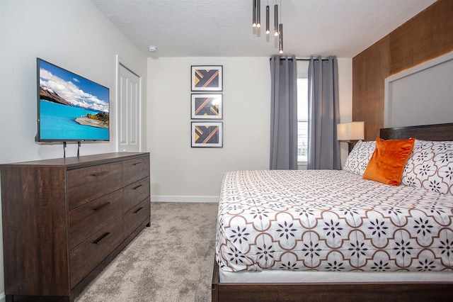 bedroom with light colored carpet and a textured ceiling