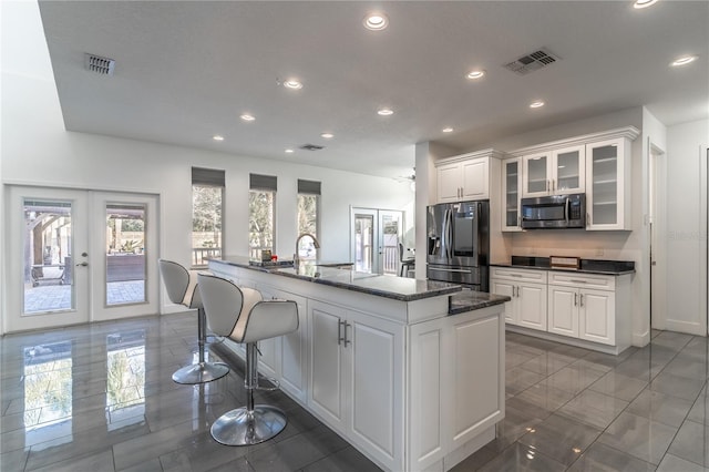 kitchen with white cabinetry, a kitchen island with sink, french doors, and appliances with stainless steel finishes