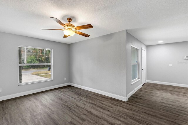 empty room with ceiling fan, dark wood-type flooring, and a textured ceiling