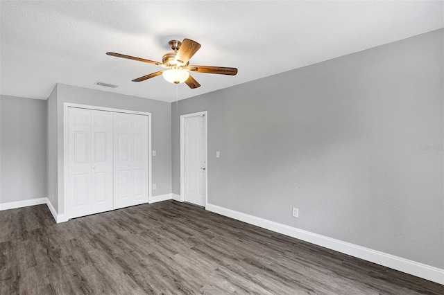 unfurnished bedroom with ceiling fan, dark hardwood / wood-style floors, a closet, and a textured ceiling