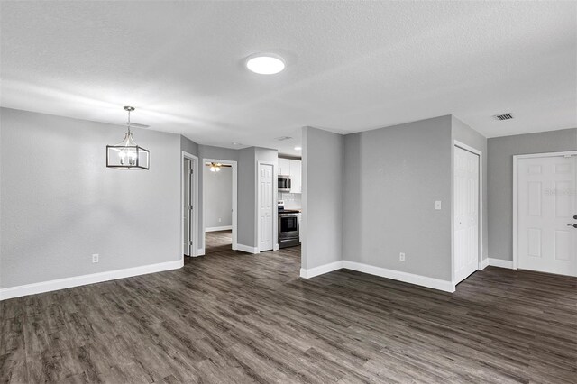 unfurnished living room with dark wood-type flooring and a textured ceiling