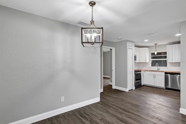 kitchen featuring appliances with stainless steel finishes, white cabinetry, hanging light fixtures, butcher block counters, and dark hardwood / wood-style flooring