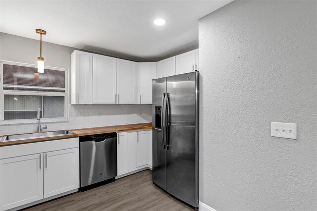 kitchen featuring sink, wooden counters, decorative light fixtures, appliances with stainless steel finishes, and white cabinets