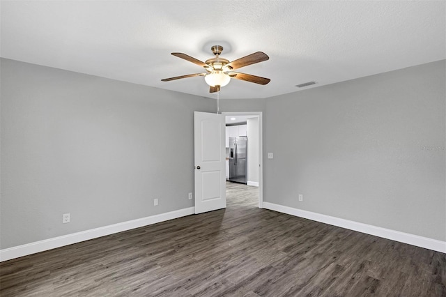 unfurnished room featuring ceiling fan, dark wood-type flooring, and a textured ceiling