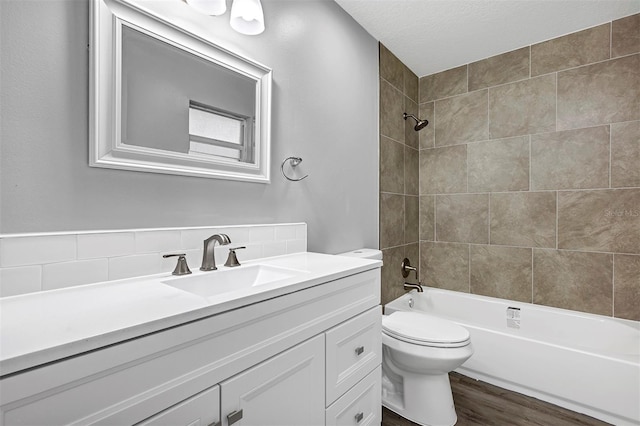 full bathroom featuring vanity, tiled shower / bath combo, toilet, and hardwood / wood-style flooring