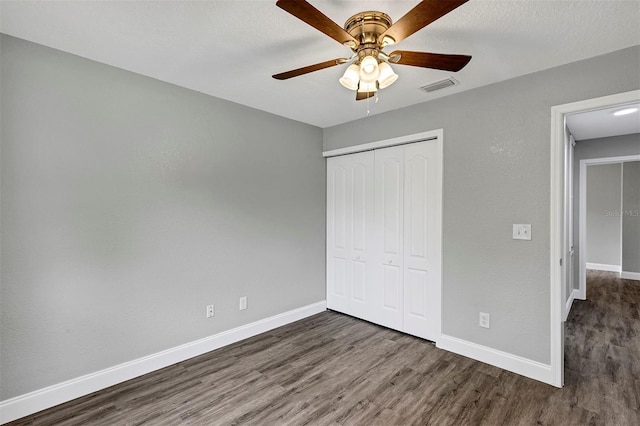 unfurnished bedroom featuring a textured ceiling, dark wood-type flooring, a closet, and ceiling fan