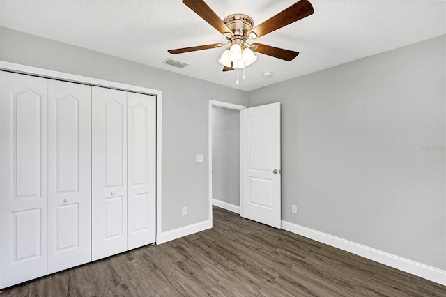 unfurnished bedroom featuring a closet, a textured ceiling, dark hardwood / wood-style floors, and ceiling fan