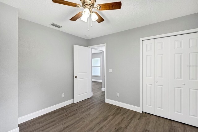 unfurnished bedroom with ceiling fan, a textured ceiling, dark hardwood / wood-style flooring, and a closet