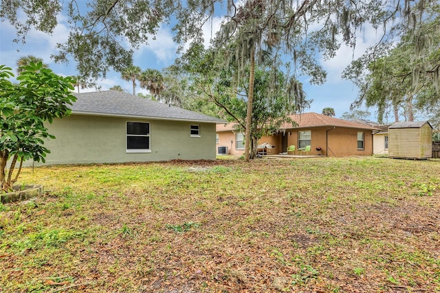 rear view of house featuring a yard, central air condition unit, and a storage shed