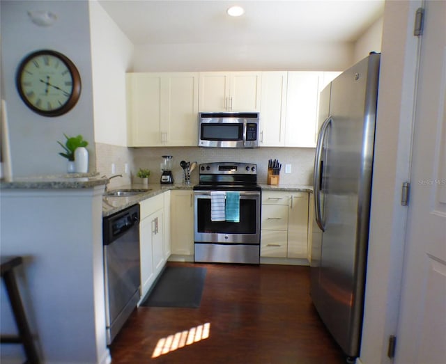 kitchen with stainless steel appliances, light stone countertops, sink, and white cabinets