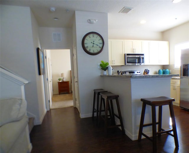 kitchen with white cabinetry, backsplash, a breakfast bar, and appliances with stainless steel finishes