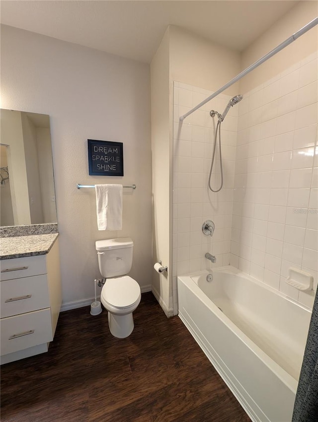 bathroom featuring shower / bath combination, baseboards, toilet, wood finished floors, and vanity