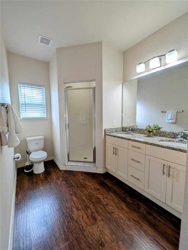 full bathroom with visible vents, toilet, wood finished floors, a shower stall, and a sink