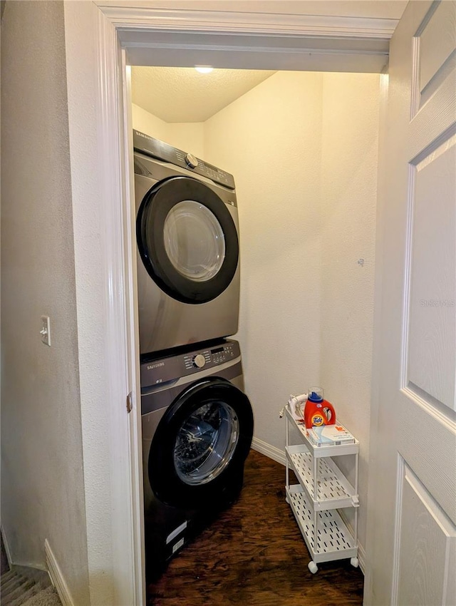 clothes washing area with dark wood-type flooring, laundry area, baseboards, and stacked washing maching and dryer