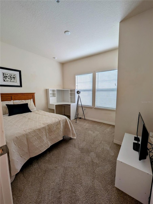 carpeted bedroom with a textured ceiling and baseboards