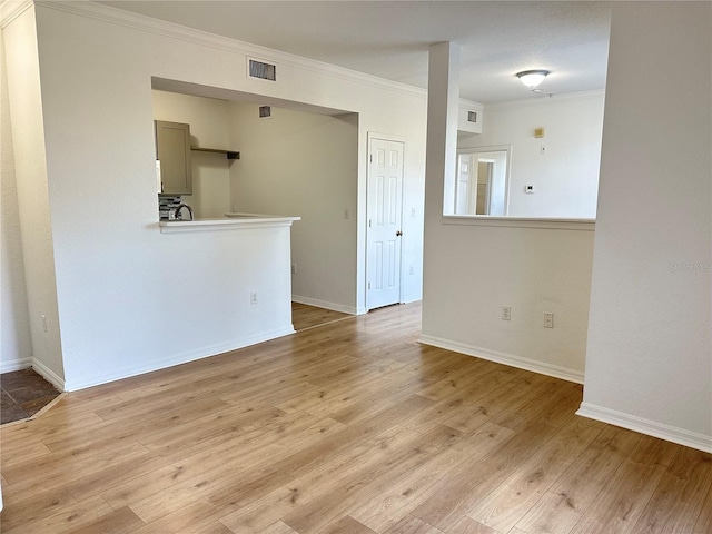 empty room with crown molding and light hardwood / wood-style flooring