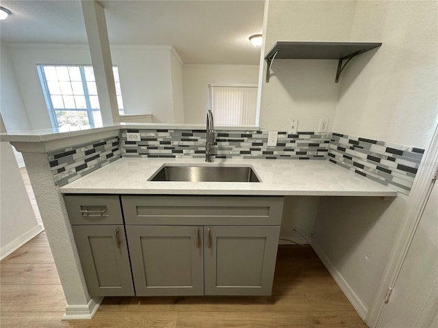 kitchen with tasteful backsplash, sink, gray cabinetry, and light wood-type flooring