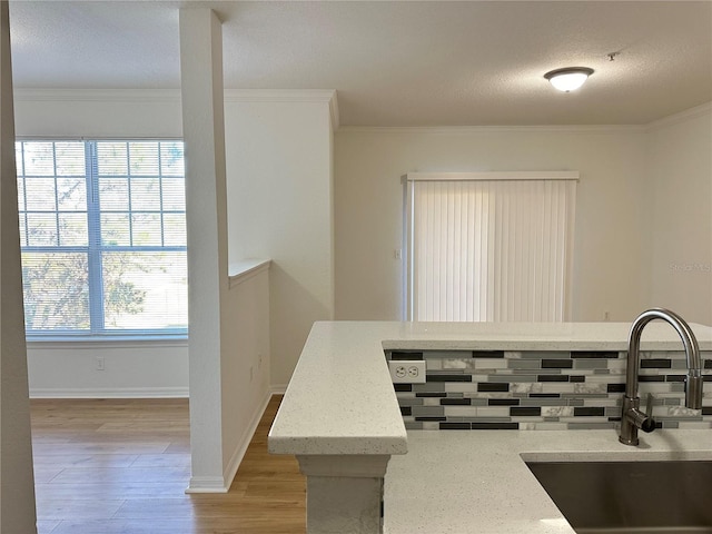 kitchen featuring crown molding, sink, a textured ceiling, and light hardwood / wood-style flooring