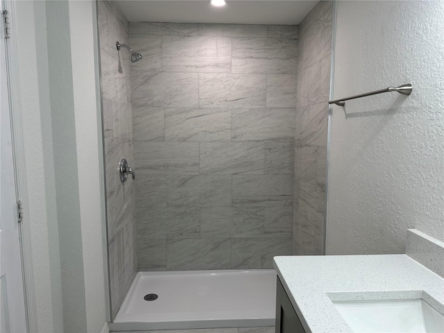 bathroom with tiled shower and vanity