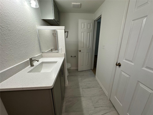 bathroom featuring vanity, a textured ceiling, and toilet