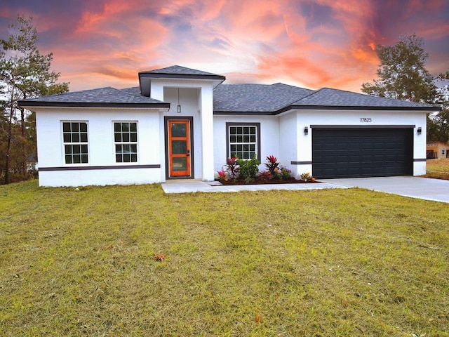 prairie-style home featuring a garage and a lawn