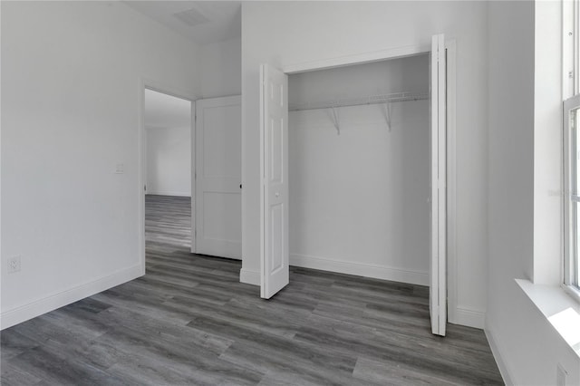 unfurnished bedroom with dark wood-type flooring and a closet