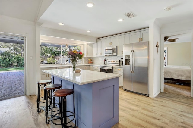 kitchen with white cabinetry, stainless steel appliances, light hardwood / wood-style floors, and tasteful backsplash