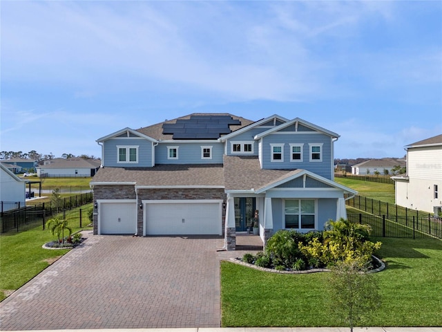 craftsman-style house featuring a garage, a front yard, and solar panels