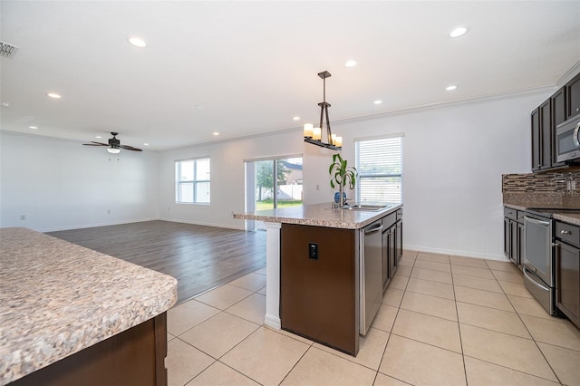 kitchen featuring appliances with stainless steel finishes, decorative light fixtures, sink, backsplash, and light tile patterned floors