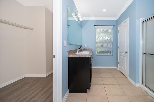 bathroom featuring tile patterned flooring, ornamental molding, vanity, and an enclosed shower