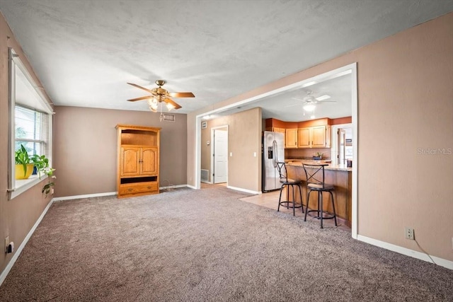 living room featuring a ceiling fan, light carpet, and baseboards