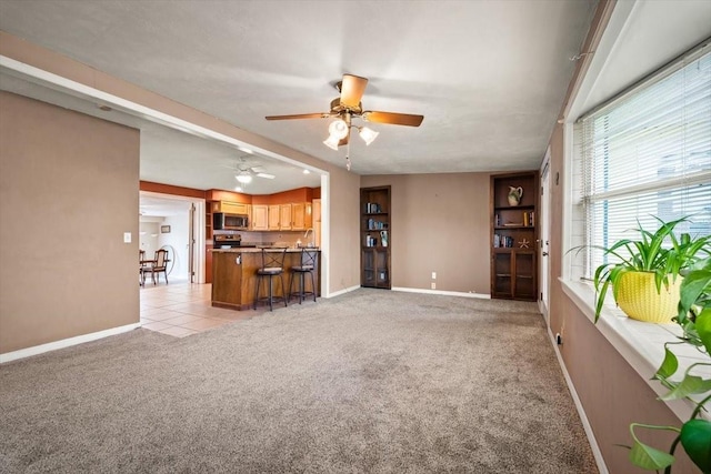 unfurnished living room with light tile patterned flooring, ceiling fan, baseboards, and light colored carpet