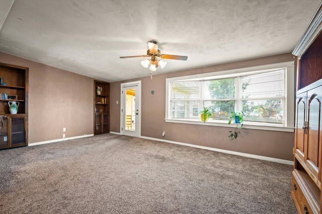 unfurnished living room featuring built in features, baseboards, a ceiling fan, a textured ceiling, and carpet flooring