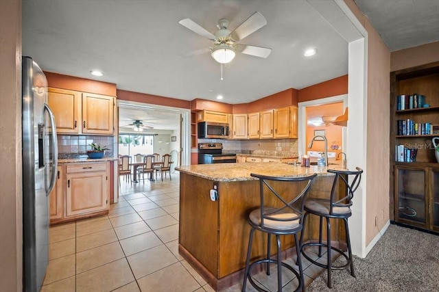 kitchen with light stone counters, light tile patterned floors, stainless steel appliances, tasteful backsplash, and a sink