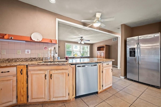 kitchen with light brown cabinets, decorative backsplash, stainless steel appliances, and a sink