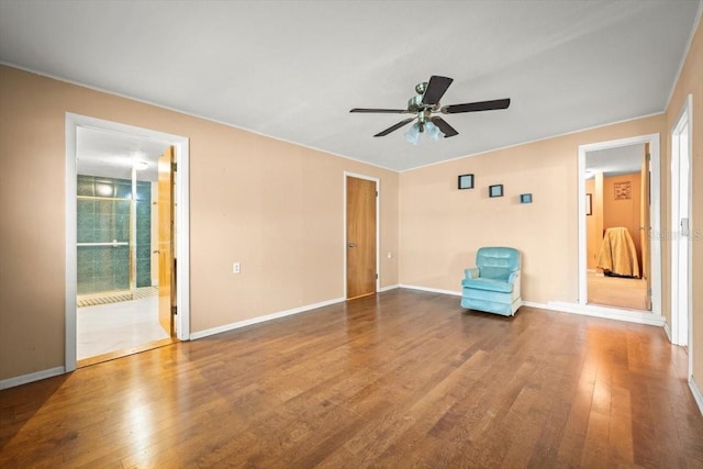 unfurnished room with wood finished floors, a ceiling fan, and baseboards