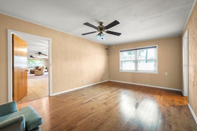 interior space featuring a ceiling fan, baseboards, and hardwood / wood-style flooring