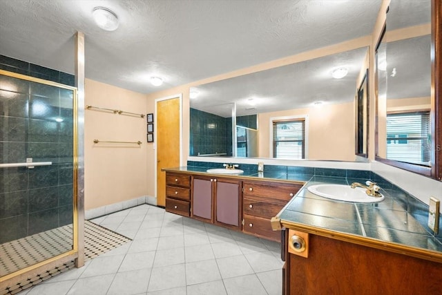 bathroom with a stall shower, vanity, a textured ceiling, and tile patterned floors