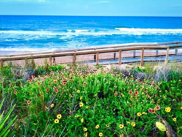 water view featuring fence and a beach view