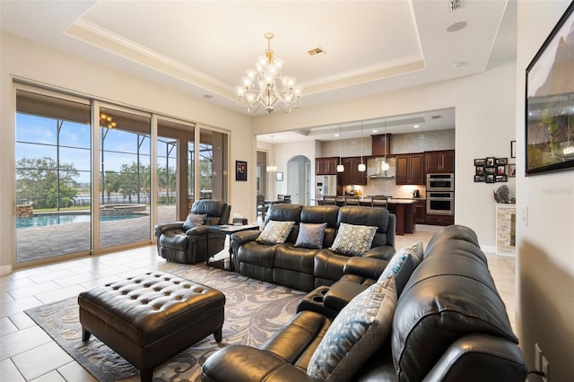 tiled living room with an inviting chandelier, ornamental molding, and a tray ceiling