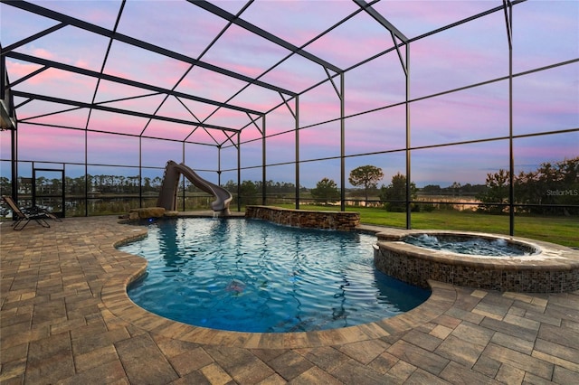 pool at dusk with a lanai, an in ground hot tub, a patio, and a water slide