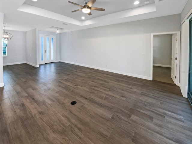 empty room with dark hardwood / wood-style flooring and a tray ceiling