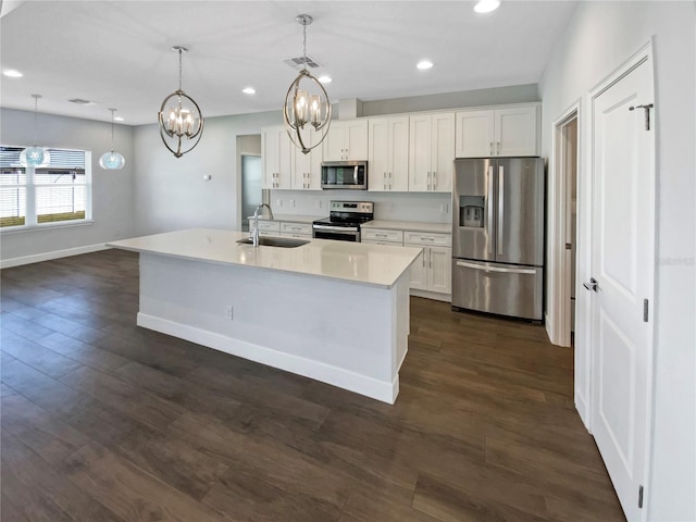 kitchen with stainless steel appliances, white cabinetry, sink, and decorative light fixtures