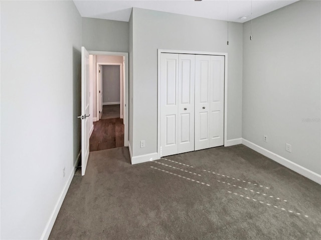 unfurnished bedroom with a closet and dark colored carpet