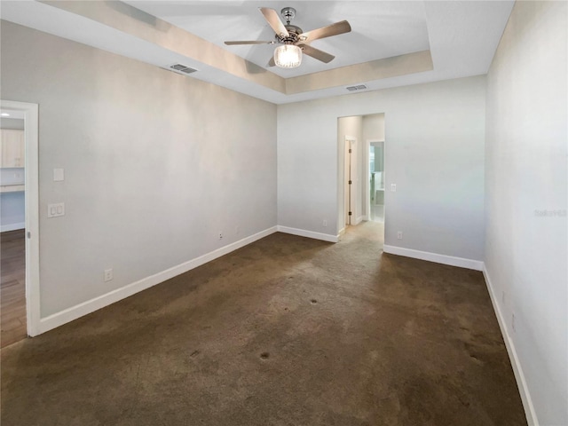 carpeted spare room with a tray ceiling and ceiling fan